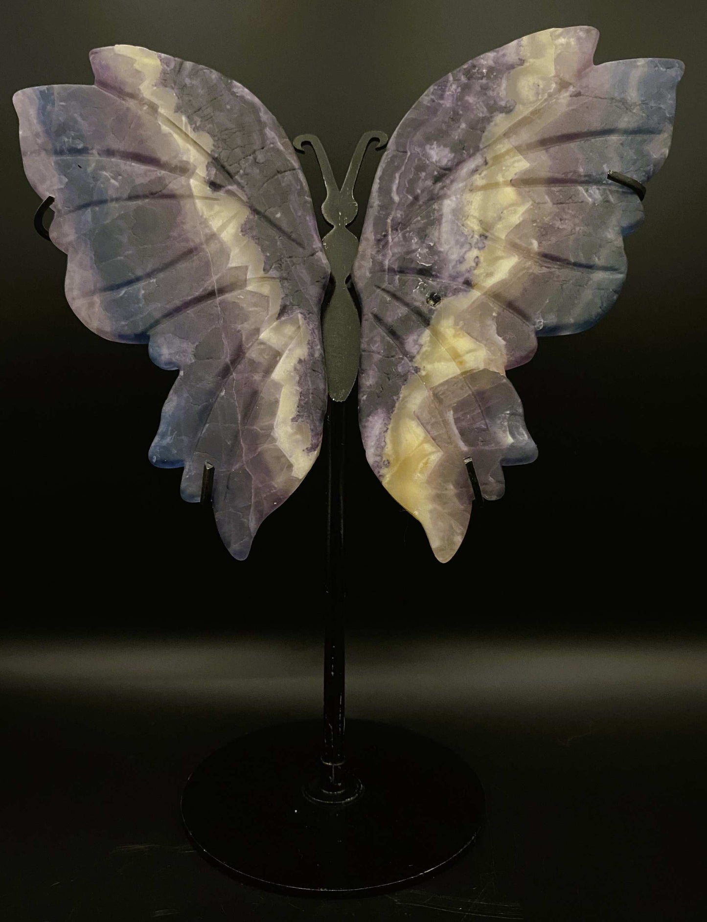 Fluture sculptat din fluorit pe suport metalic negru, piatra semiprețioasă violet cu dungi albe.