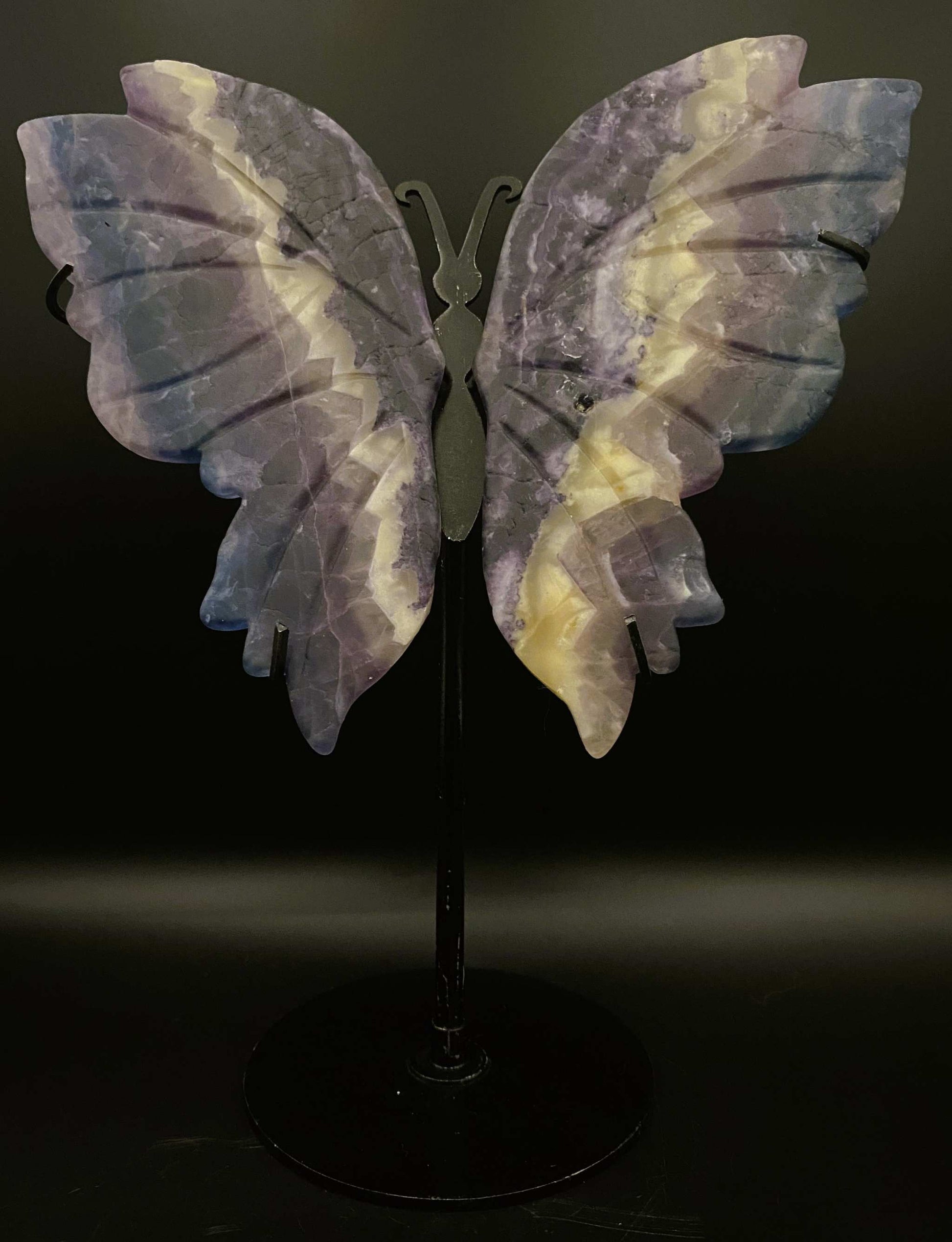 Fluture sculptat din fluorit pe suport metalic negru, piatra semiprețioasă violet cu dungi albe.