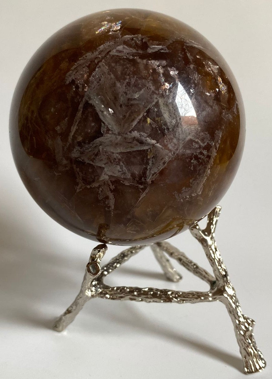 Sfera din cristal de fluorit cu suport metalic pe fundal alb