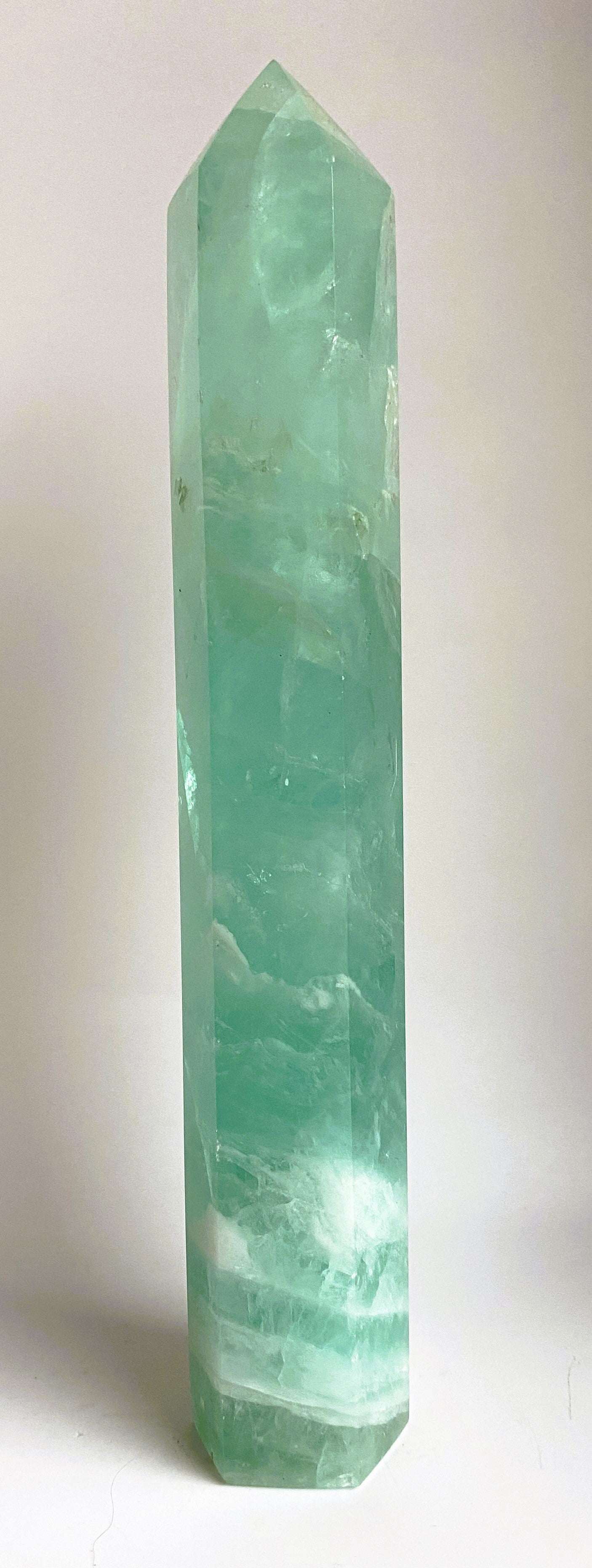 Green Fluorit Verde obelisk gemstone with natural patterns on white background