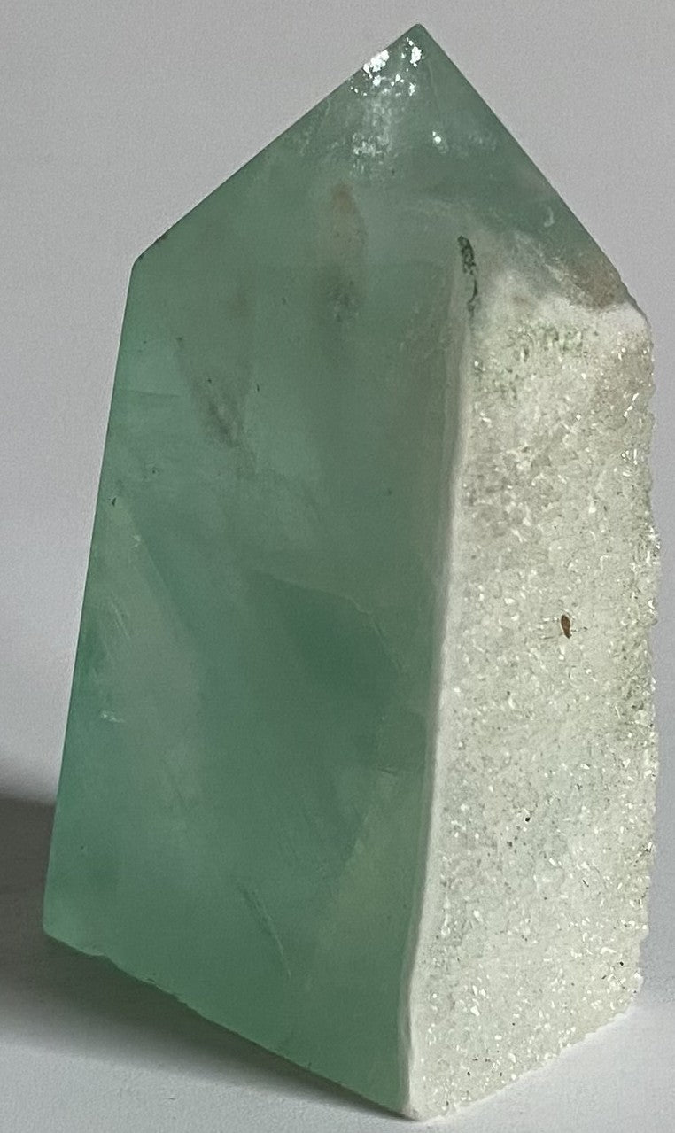 Obelisc brut din cristal de fluorit verde pe fundal alb