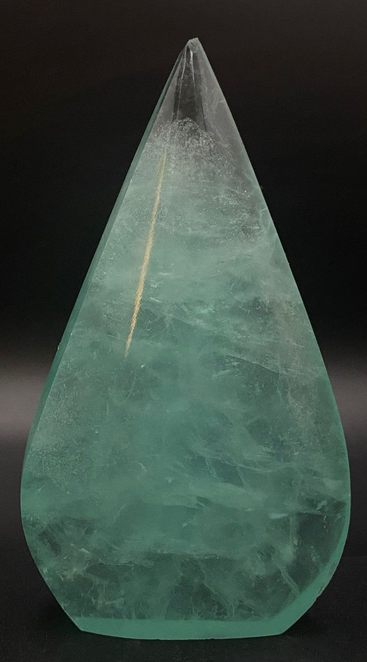 Sculptura din fluorit verde pe fundal negru sub lumina artificiala