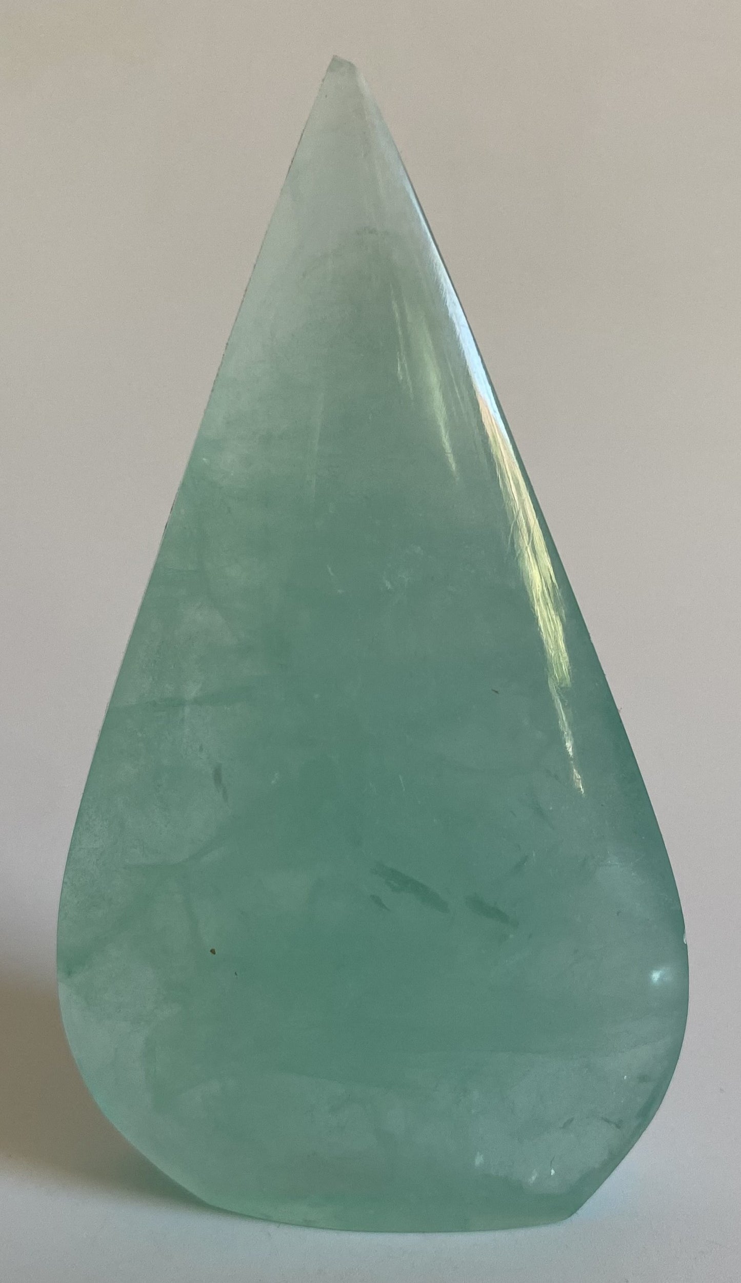 Sculptura din fluorit verde pe fundal alb sub lumina naturala