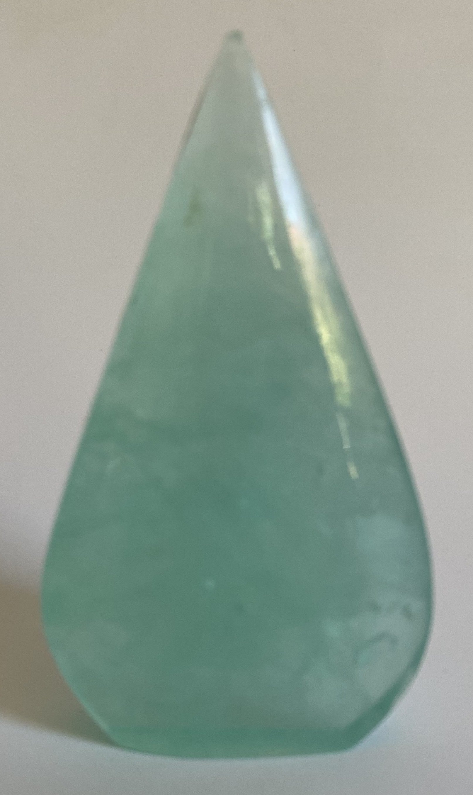 Sculptura din fluorit verde pe fundal alb sub lumina naturala