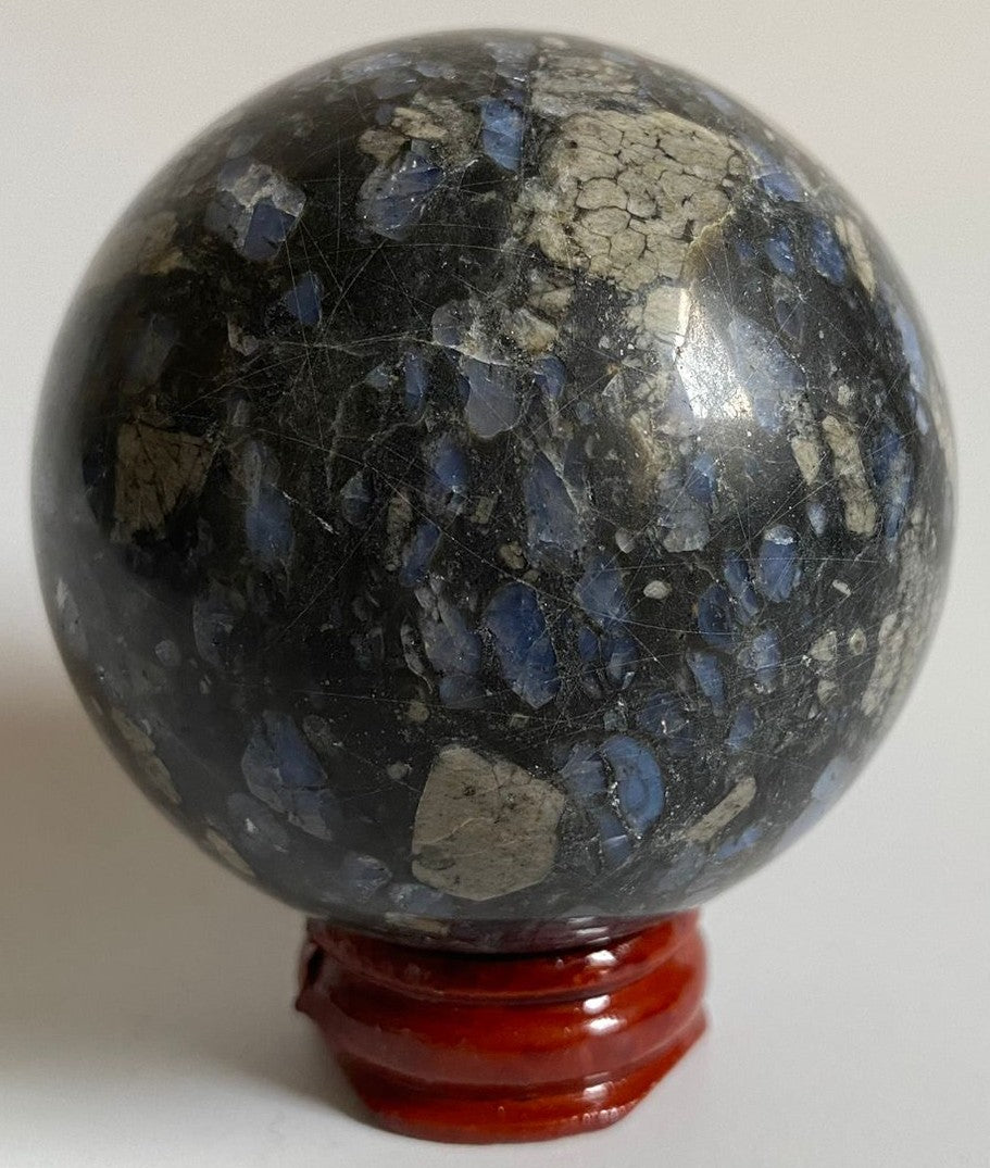 Sfera din cristal de glaucofan pe suport din lemn cu fundal alb