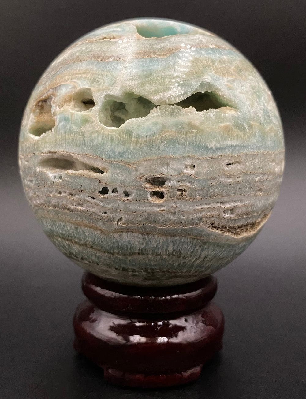 Sfera din piatra semipretioasa de hemimorfit pe suport din lemn cu fundal negru