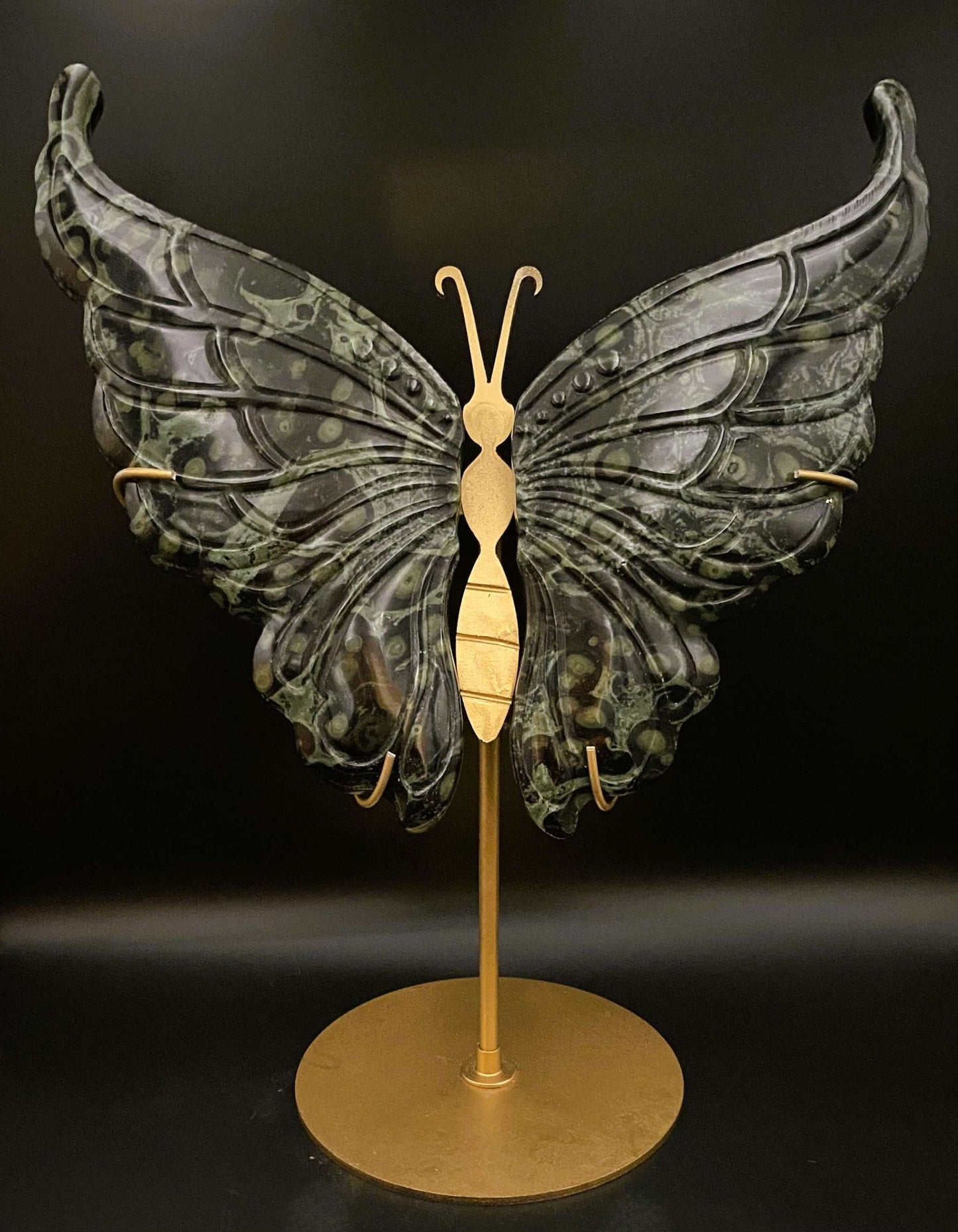 Butterfly sculpture made of Jasp Kambaba stone with metal stand on black background