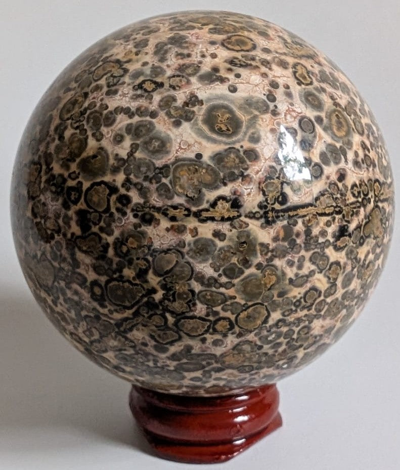 Sfera din cristal de jasp leopard pe suport din lemn cu fundal alb