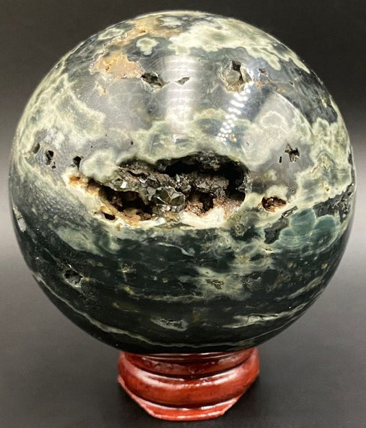 Sfera din piatra semipretioasa de jasp oceanic verde pe suport din lemn cu fundal negru