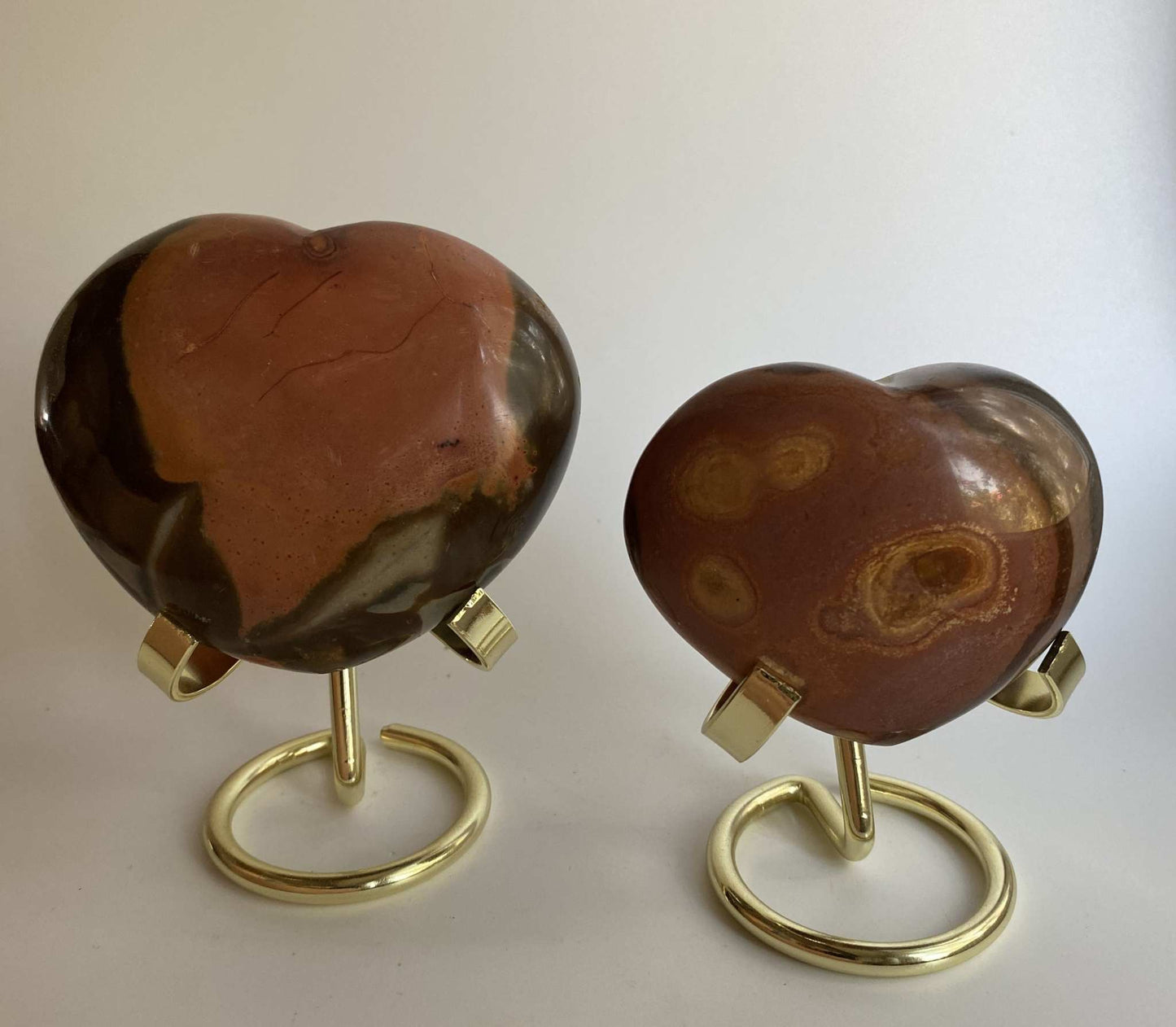 Two heart-shaped Jasp Policrom stones on metal stands set