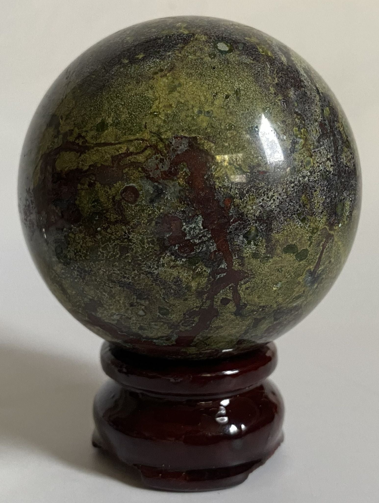 Sfera din cristal de jasp sangele dragonului pe suport din lemn cu fundal alb
