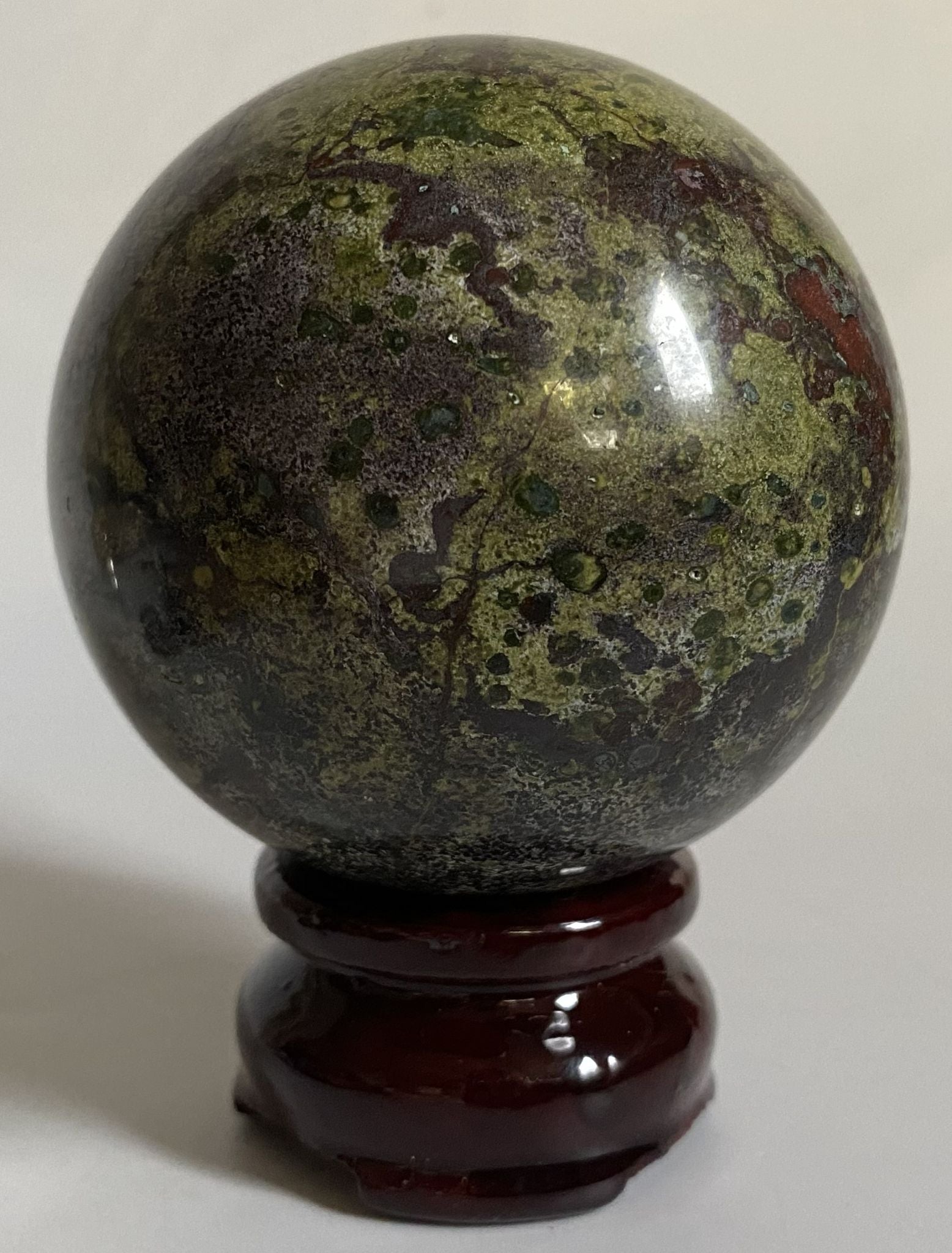 Sfera de 6.8cm din piatra semipretioasa de jasp sangele dragonului pe suport din lemn cu fundal alb