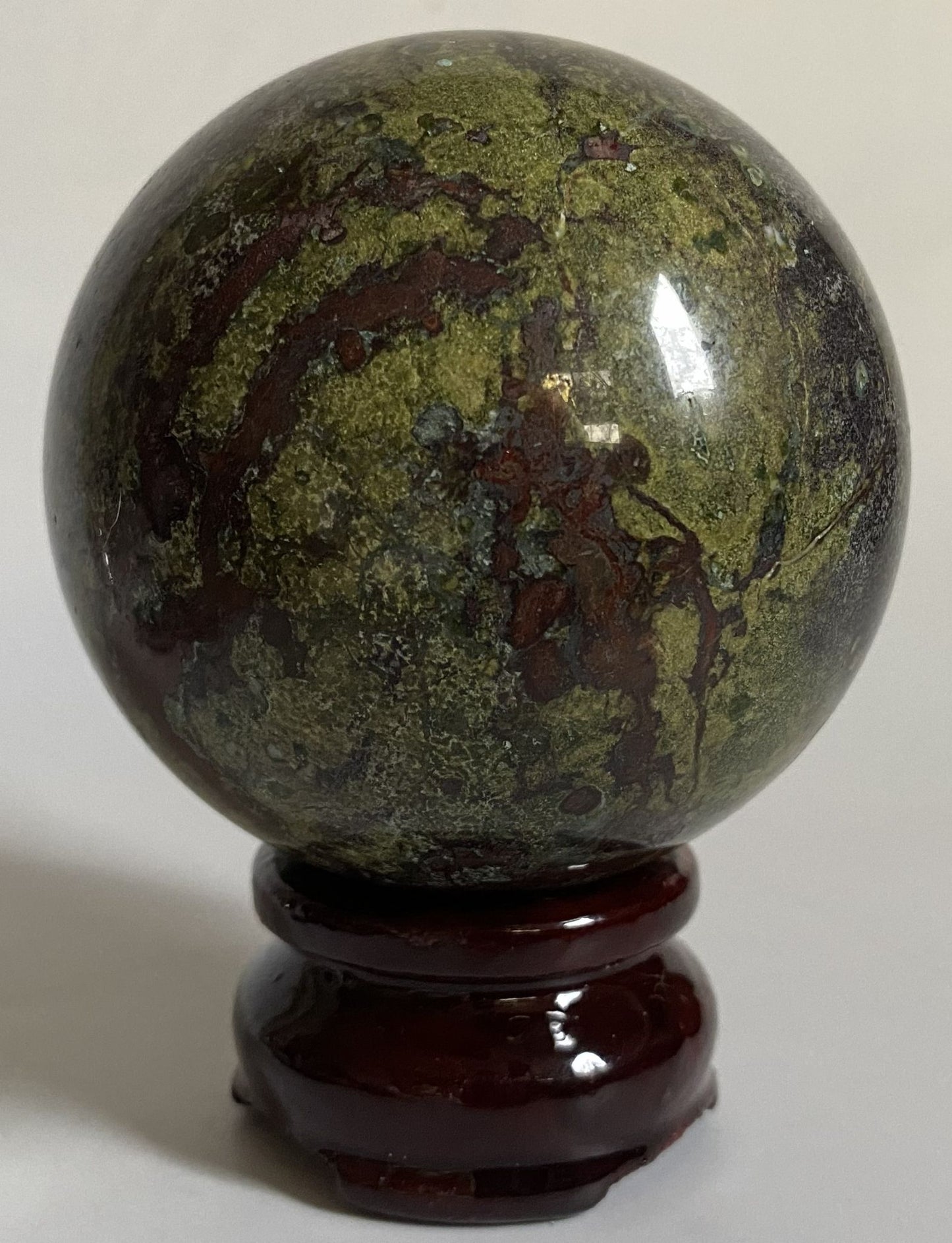 Sfera decorativa de 6.8cm din cristal de jasp sangele dragonului pe suport din lemn cu fundal alb