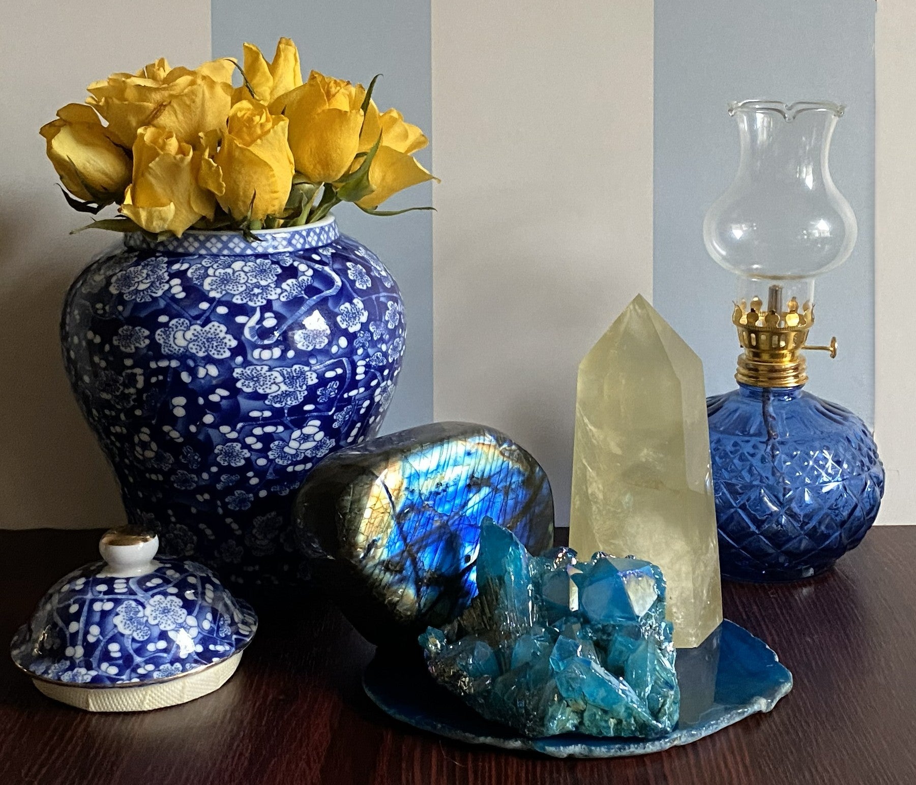 Decor cu set de cristale format din labradorit, citrin si cuart aura albastru pe felie de agat albastru cu vaza cu trandafiri galbeni