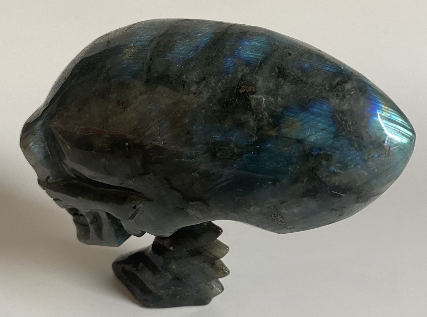 Craniu sculptat din cristal de labradorit pe fundal alb