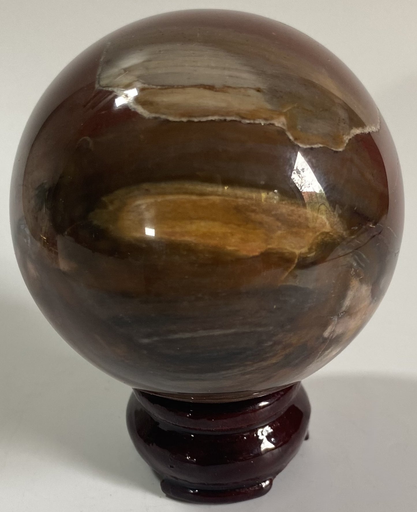 Sfera din cristal de lemn fosilizat pe suport din lemn cu fundal alb
