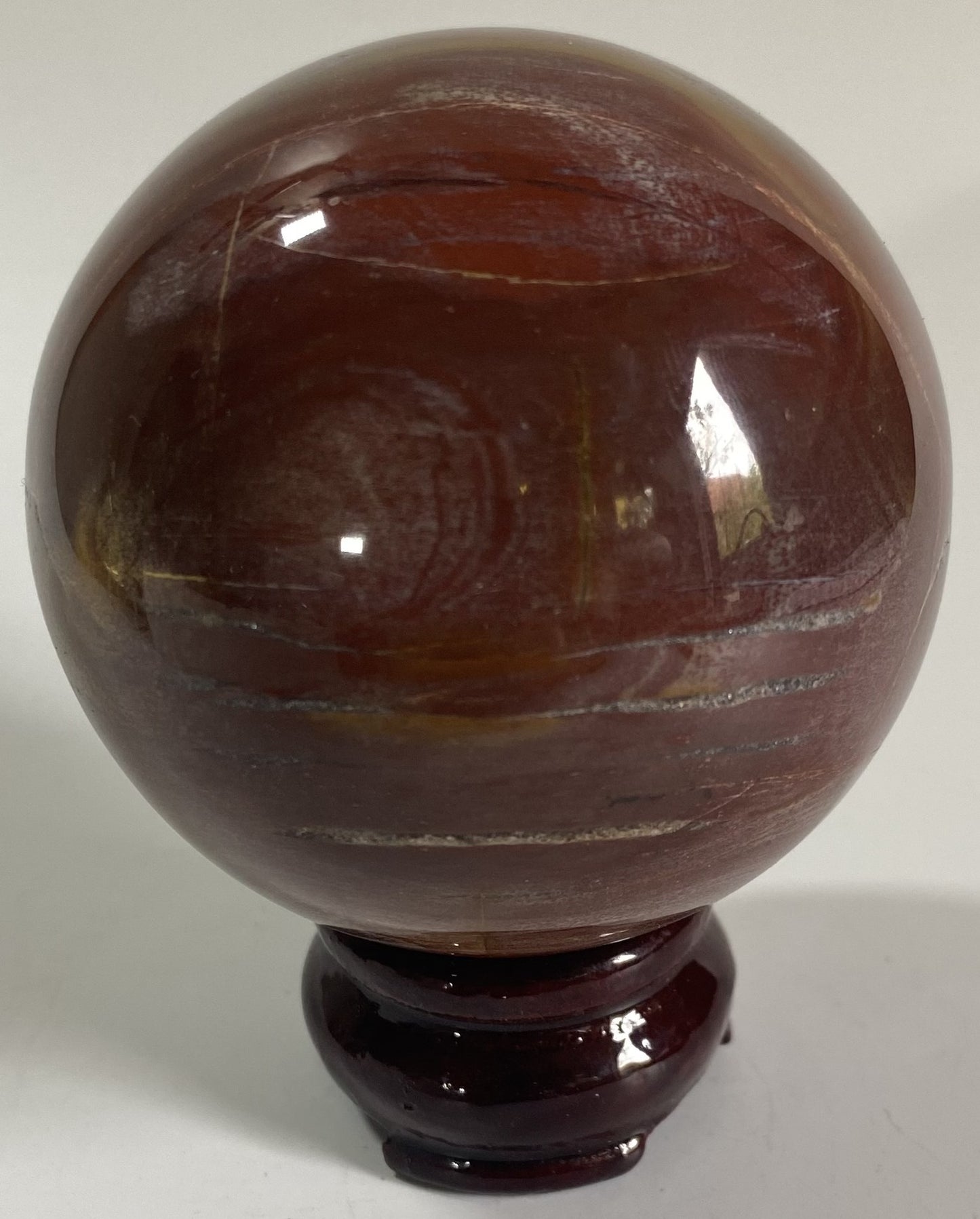 Sfera de 7cm din cristal de lemn fosilizat pe suport din lemn cu fundal alb