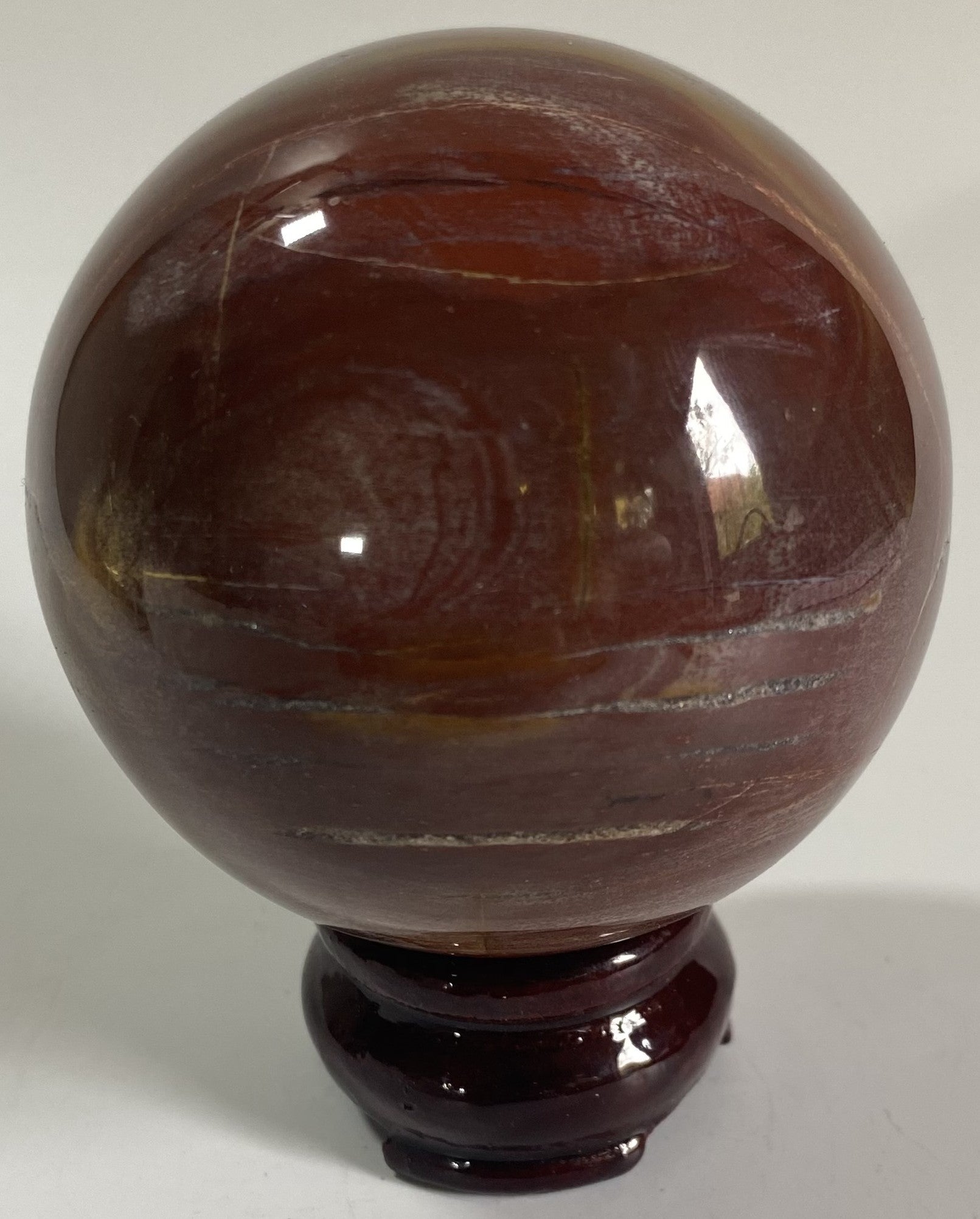 Sfera de 7cm din cristal de lemn fosilizat pe suport din lemn cu fundal alb