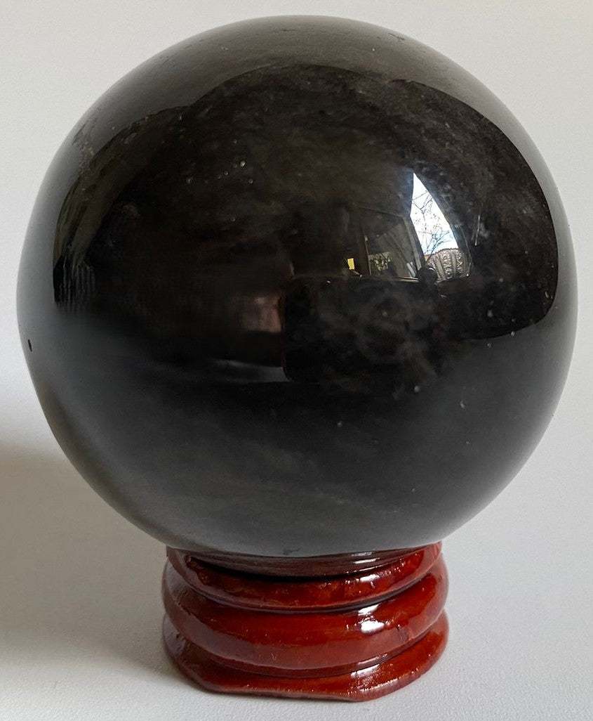 Sfera de 5.4cm din cristal de obsidian argintiu pe suport din lemn cu fundal negru