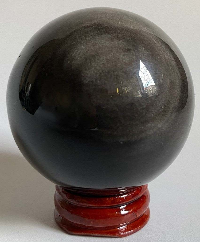 Sfera decorativa de 5.4cm din piatra semipretioasa de obsidian argintiu pe suport din lemn cu fundal negru