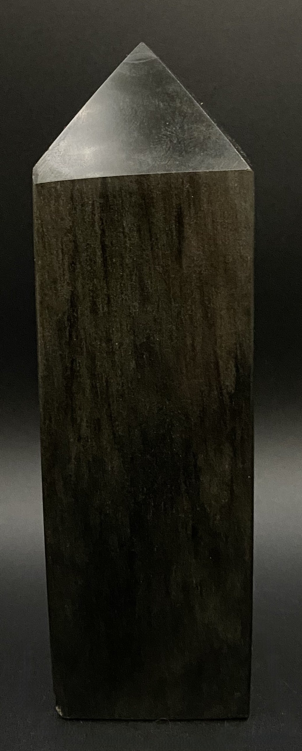 Obelisc din mineral de obsidian auriu pe fond negru si in lumina artificiala