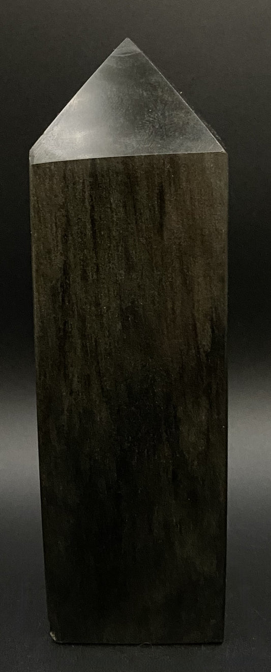 Obelisc din mineral de obsidian auriu pe fond negru si in lumina artificiala