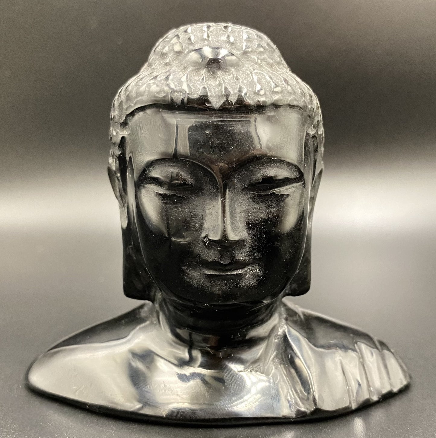 Sculptura cap de Buddha din obsidian negru cu fundal negru sub lumina artificiala