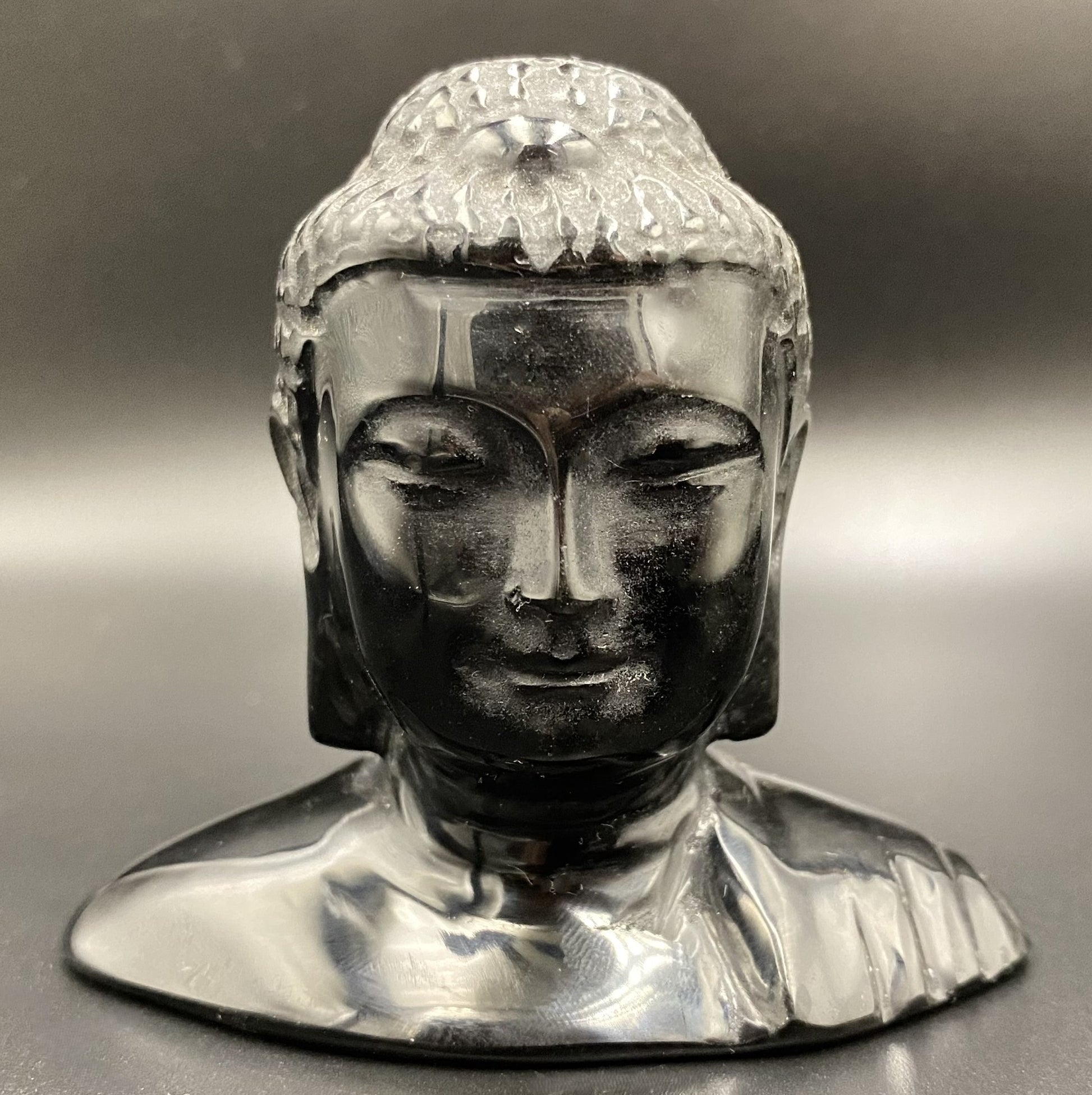 Sculptura cap de Buddha din obsidian negru cu fundal negru sub lumina artificiala