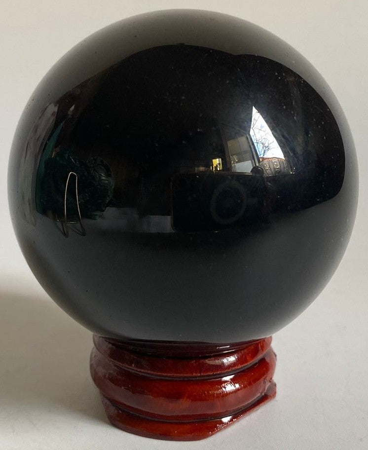 Sfera din piatra semipretioasa de obsidian curcubeu pe suport din lemn cu fundal alb
