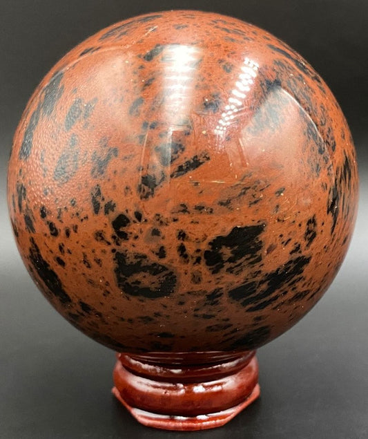 Sfera din piatra semipretioasa de obsidian mahon pe suport din lemn cu fundal negru