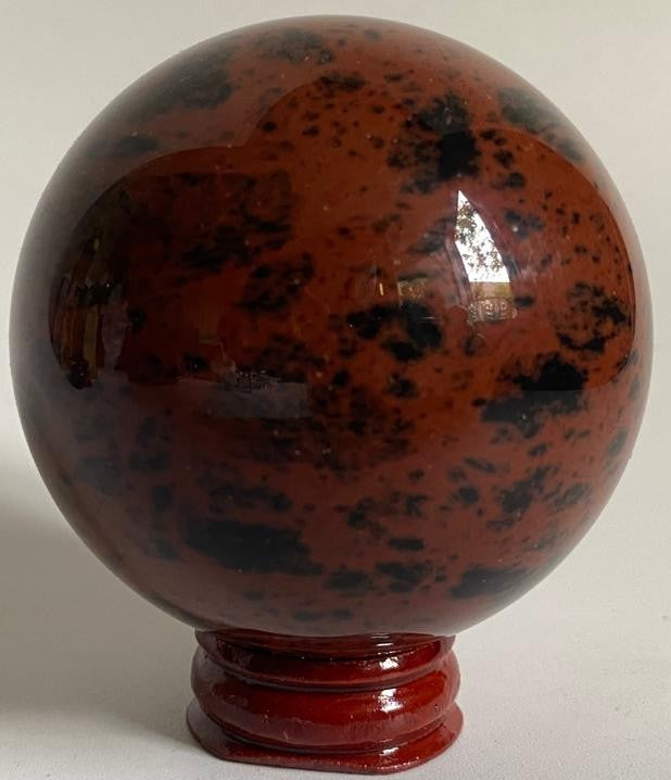 Sfera din piatra semipretioasa de obsidian mahon pe suport din lemn cu fundal alb