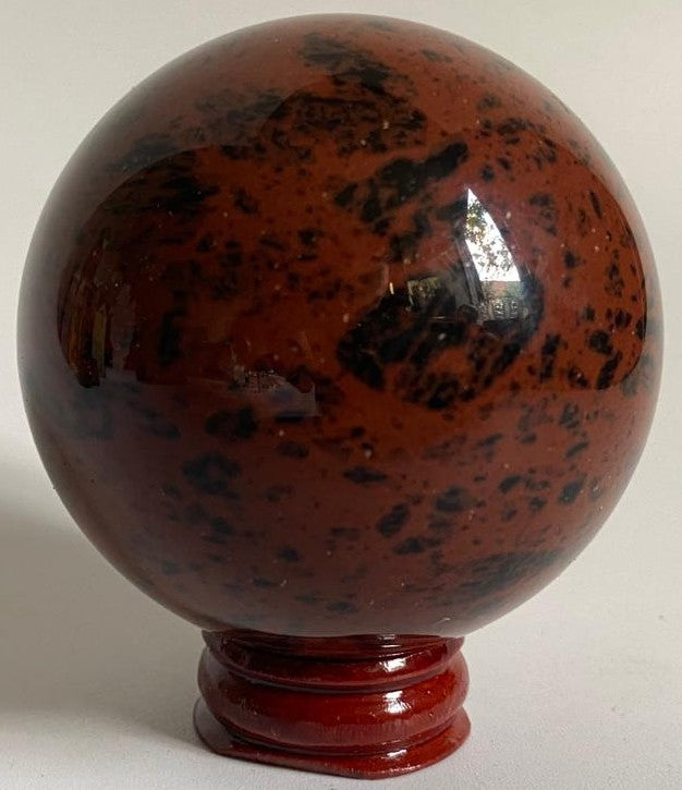 Sfera de 6.5cm din piatra semipretioasa de obsidian mahon pe suport din lemn cu fundal alb