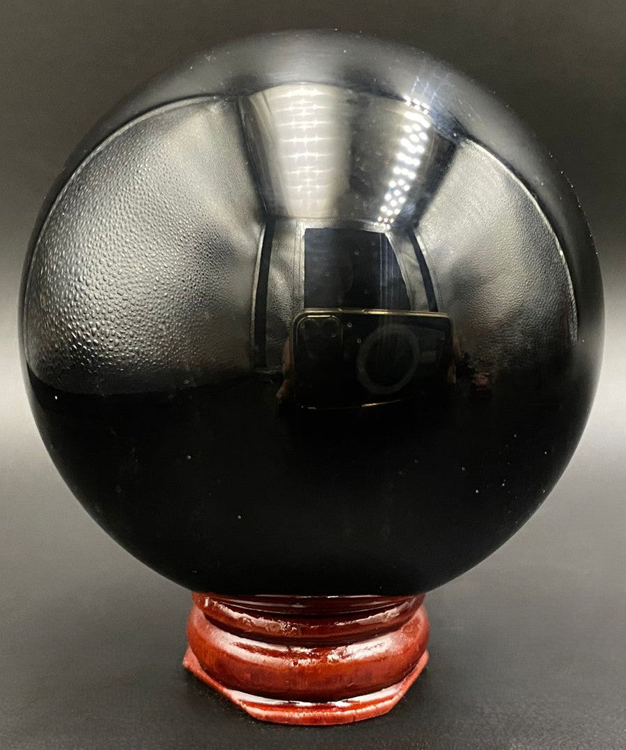 Sfera din piatra semipretioasa de obsidian negru pe fundal negru
