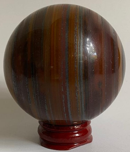 Sfera de 6.3cm din cristal de ochi de tigru cu fier pe suport din lemn cu fundal alb