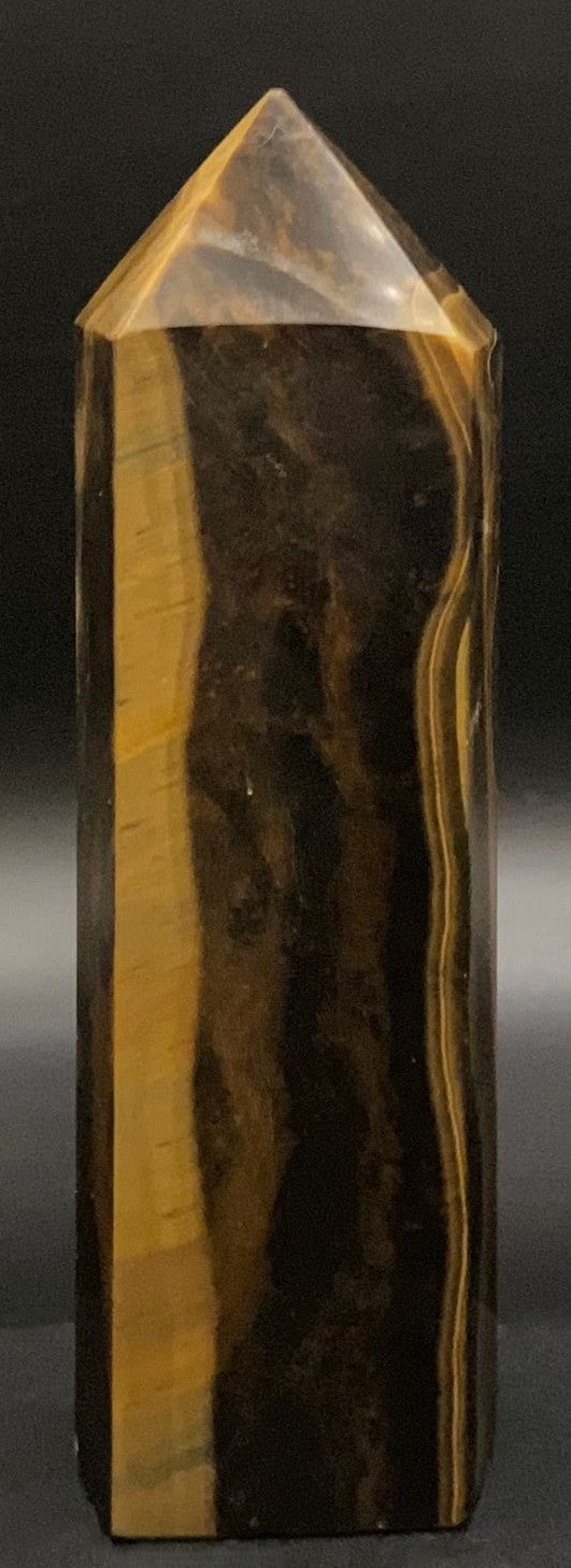 Obelisc din mineral de ochi de tigru pe fundal negru sub lumina artificiala