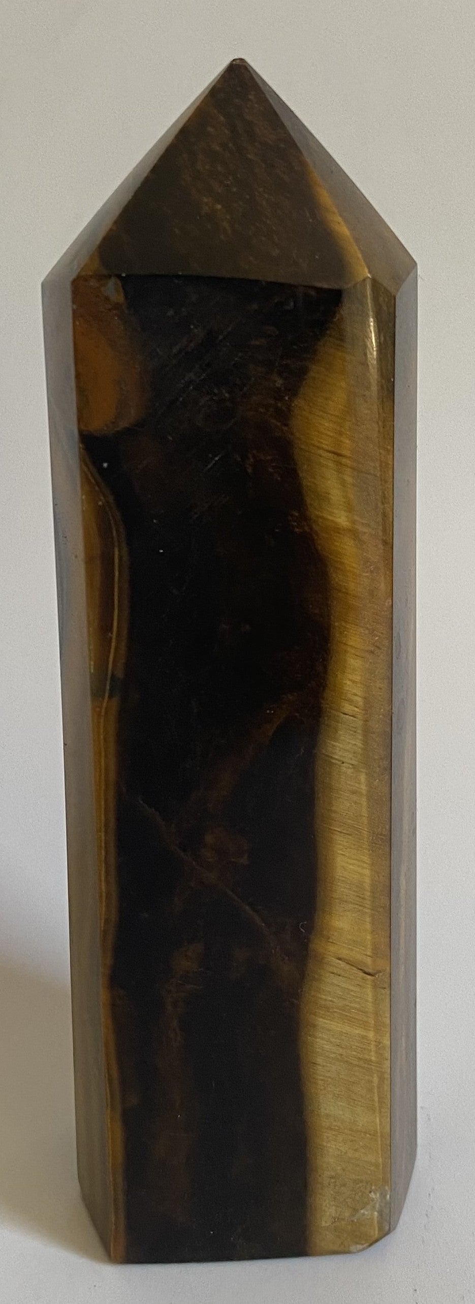 Obelisc din mineral de ochi de tigru pe fundal alb sub lumina naturala