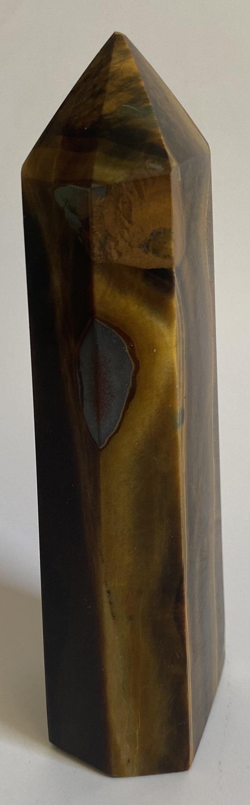 Obelisc din mineral de ochi de tigru pe fundal alb sub lumina naturala