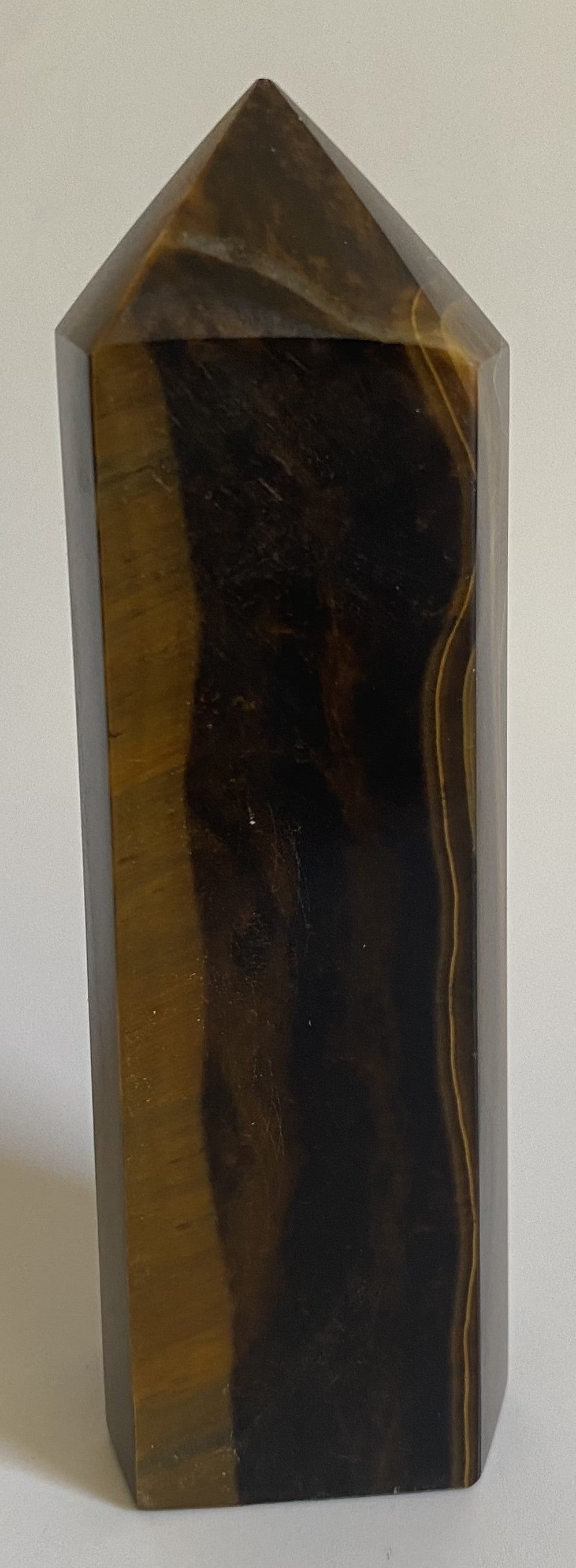 Obelisc din mineral de ochi de tigru pe fundal alb sub lumina naturala