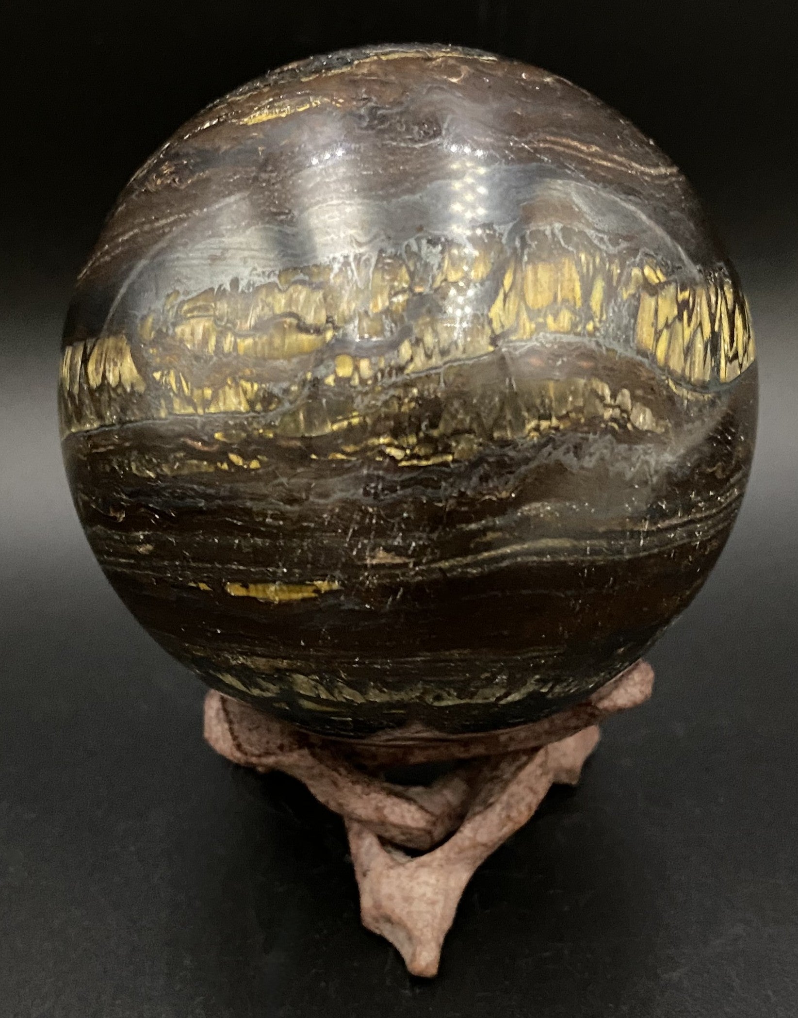 Sfera din ochi de tigru cu fier pe fond negru sub lumina artificiala
