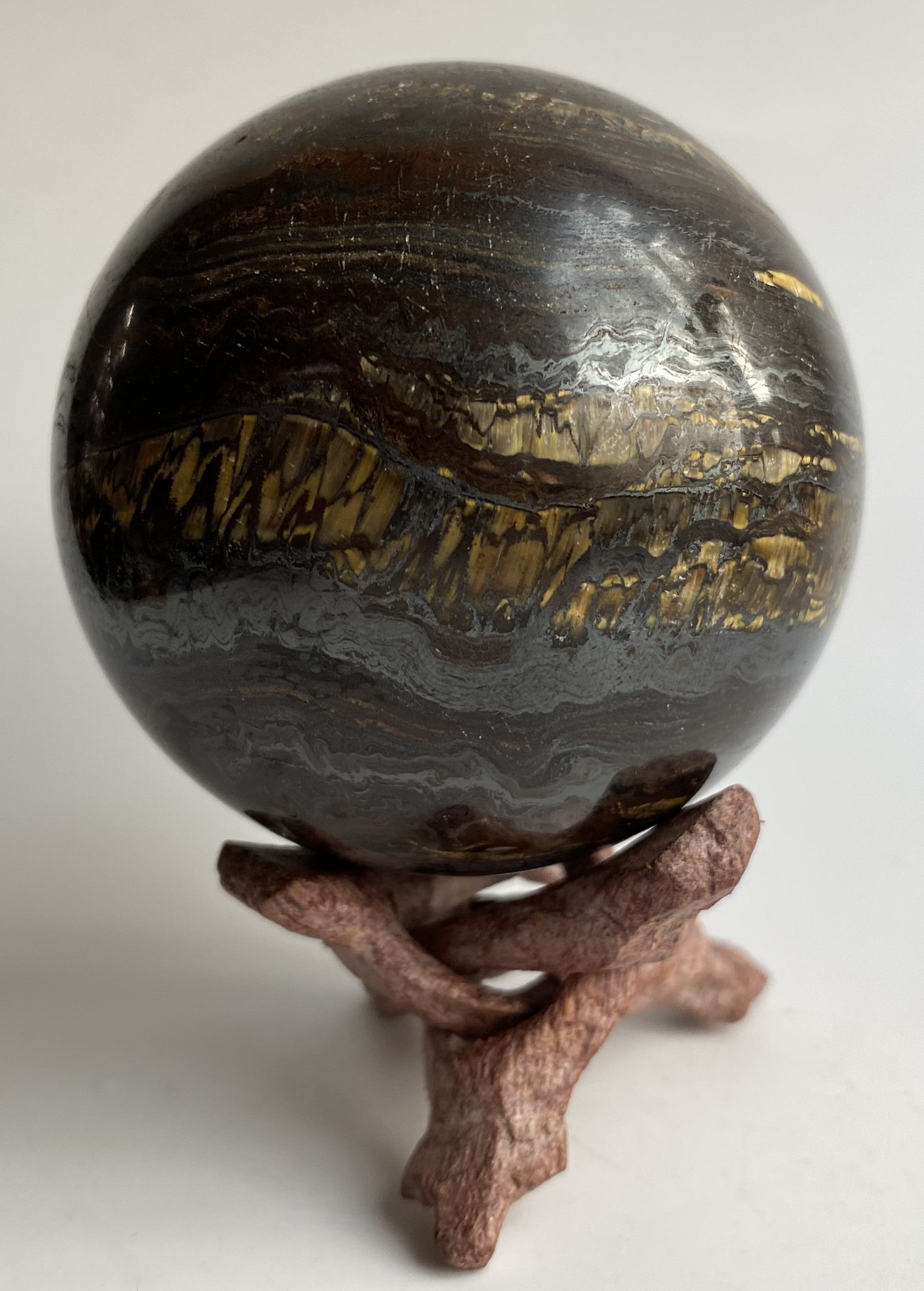 Sfera din ochi de tigru cu fier pe fond alb sub lumina naturala