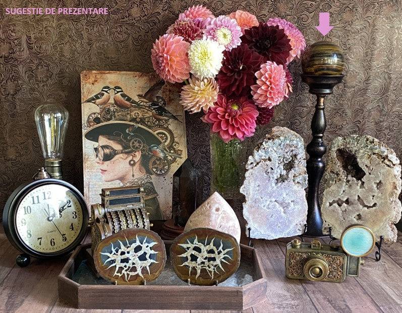 Ochi de Tigru cu Fier semi-precious stone sphere on black stand among vintage decor and flowers