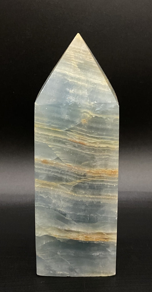 Obelisc din mineral de onix albasatru pe fundal negru sub lumina artificiala