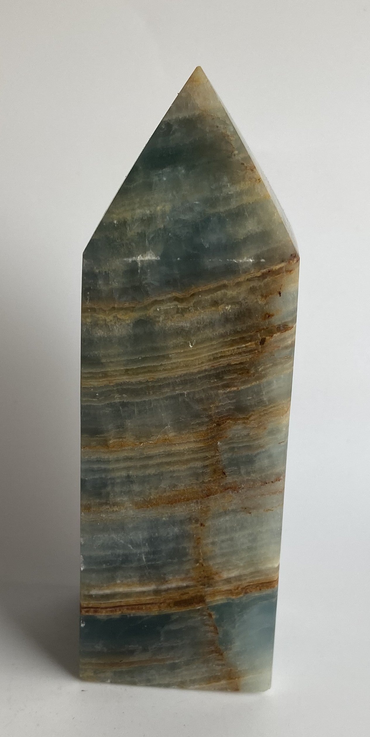 Obelisc din mineral de onix albasatru pe fundal alb sub lumina naturala