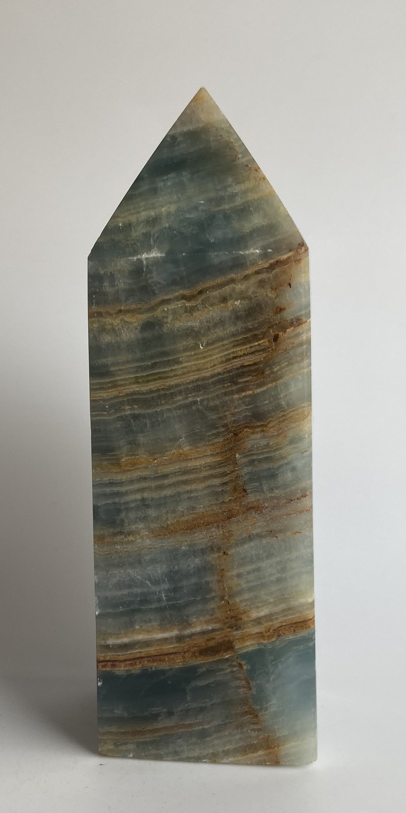 Obelisc din mineral de onix albasatru pe fundal alb sub lumina naturala
