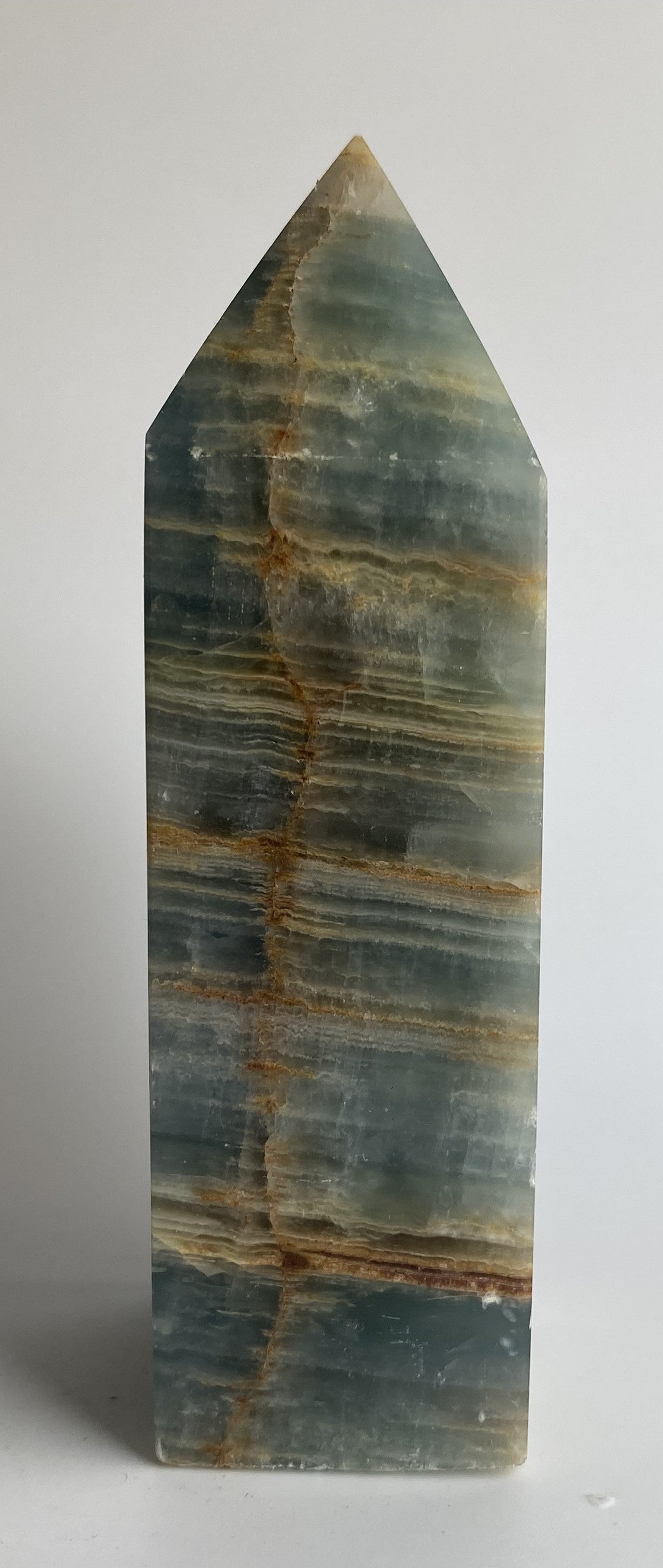 Obelisc din mineral de onix albasatru pe fundal alb sub lumina naturala
