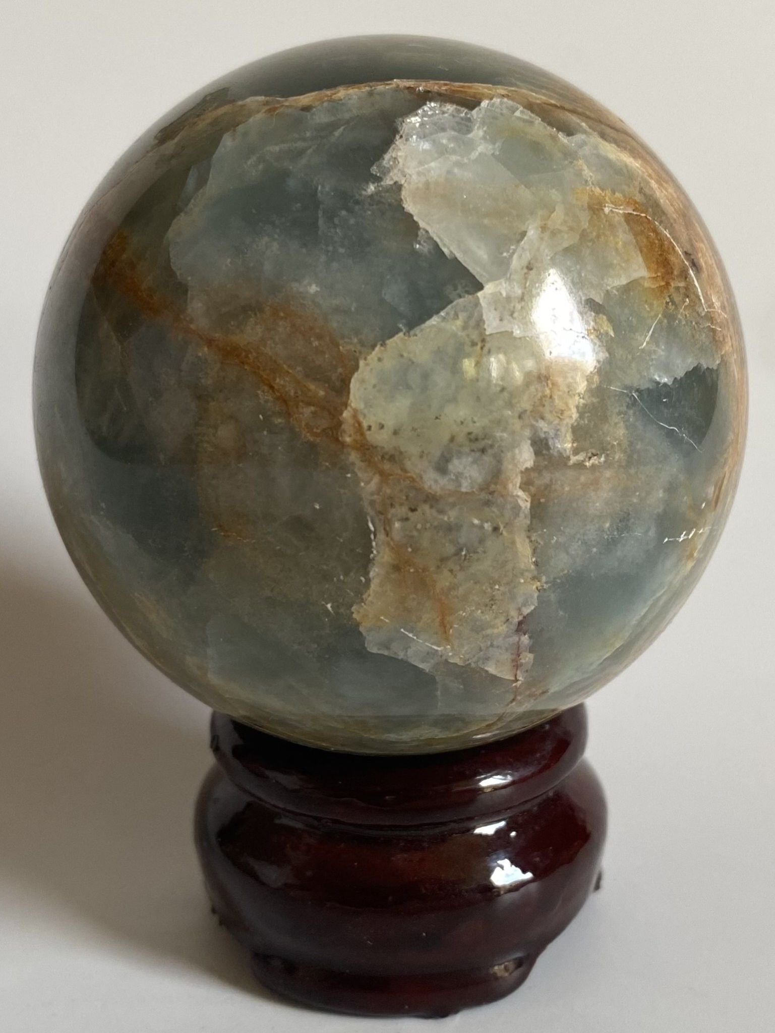Sfera din cristal de onix albastru pe suport din lemn cu fundal alb