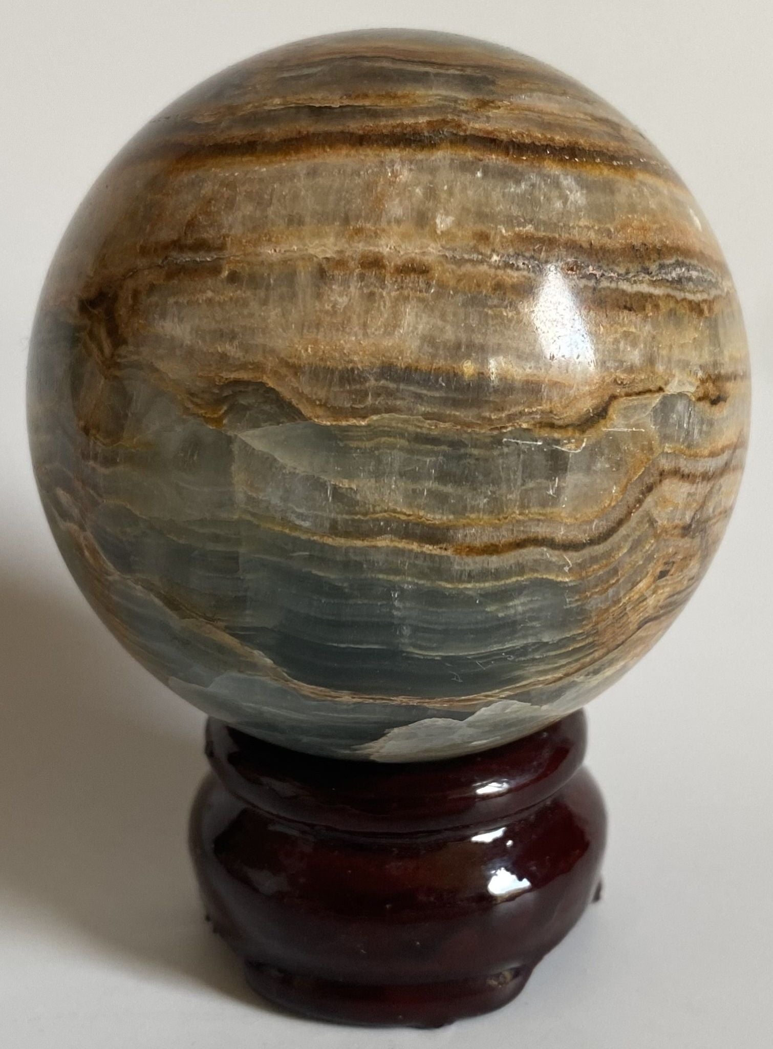Sfera de 6.4cm din piatra semipretioasa de onix albastru pe suport din lemn cu fundal alb