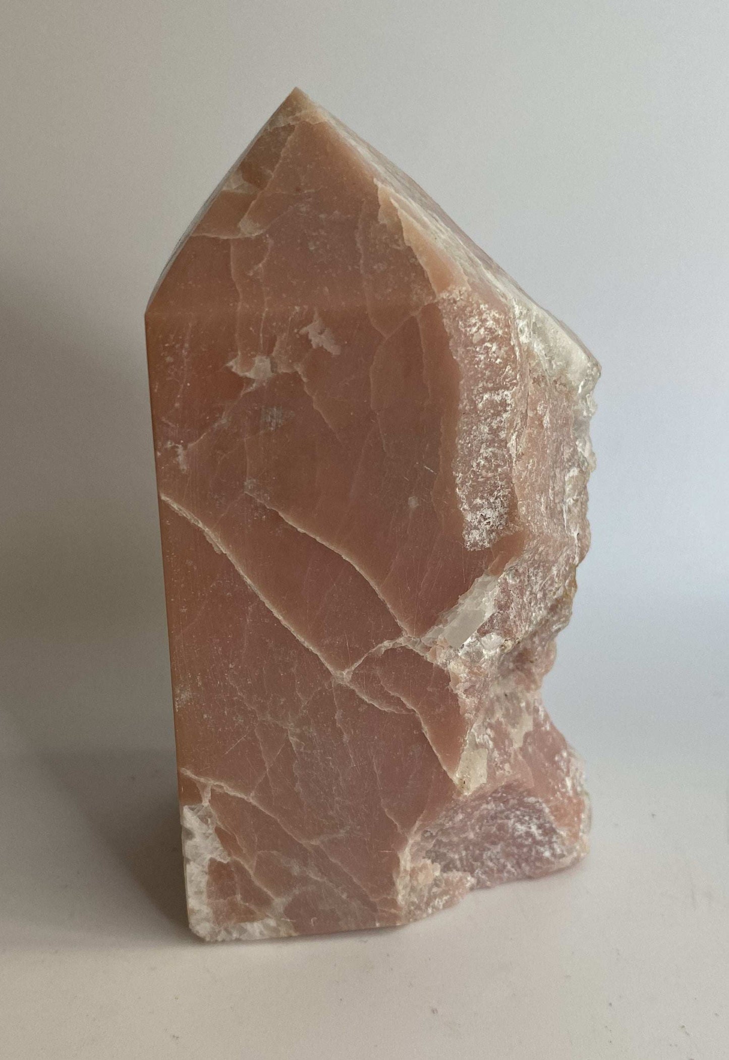 Raw pink opal obelisk gemstone with natural texture and pointed shape