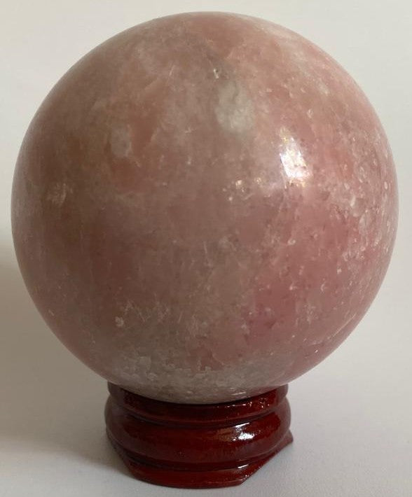 Sfera din cristal de opal roz pe suport din lemn cu fundal alb