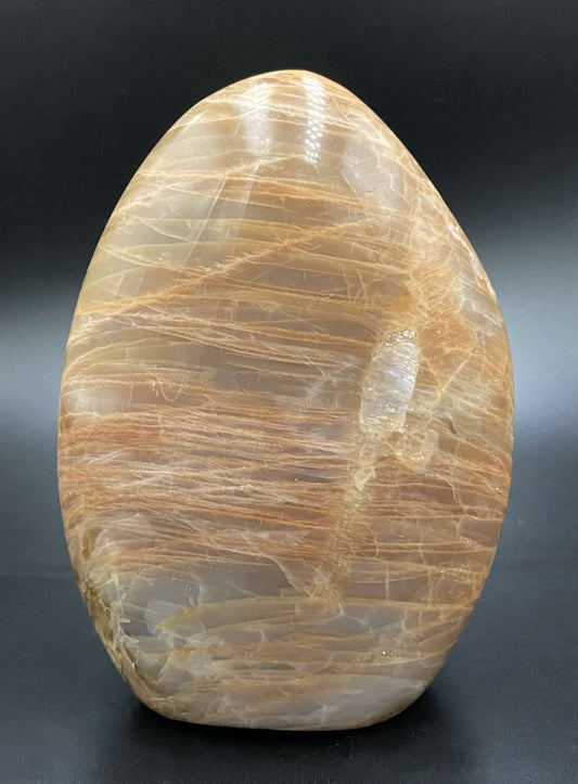 Piatra Lunii Piersica semiprecious stone sculpture with peach hues on black background